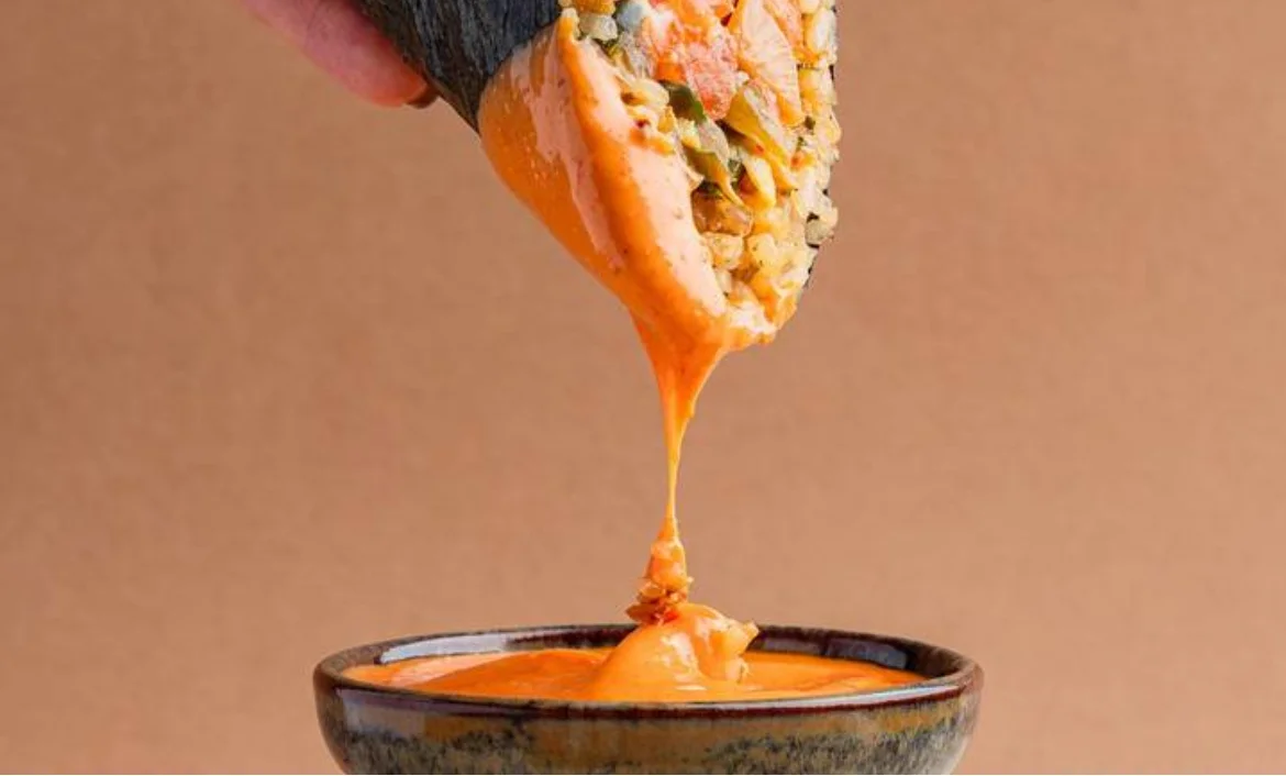 Japanese sushi roll dipped in spicy sauce