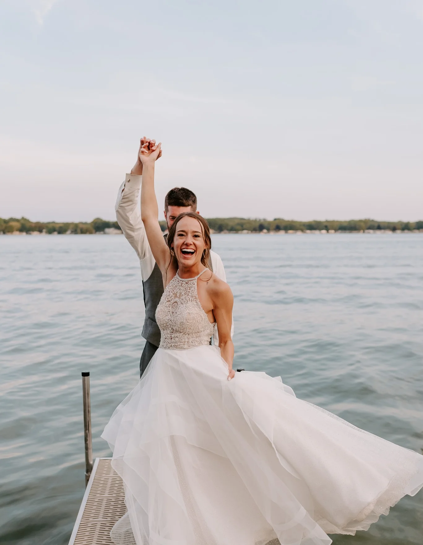 Bride joyfully celebrating on a dock by the water
