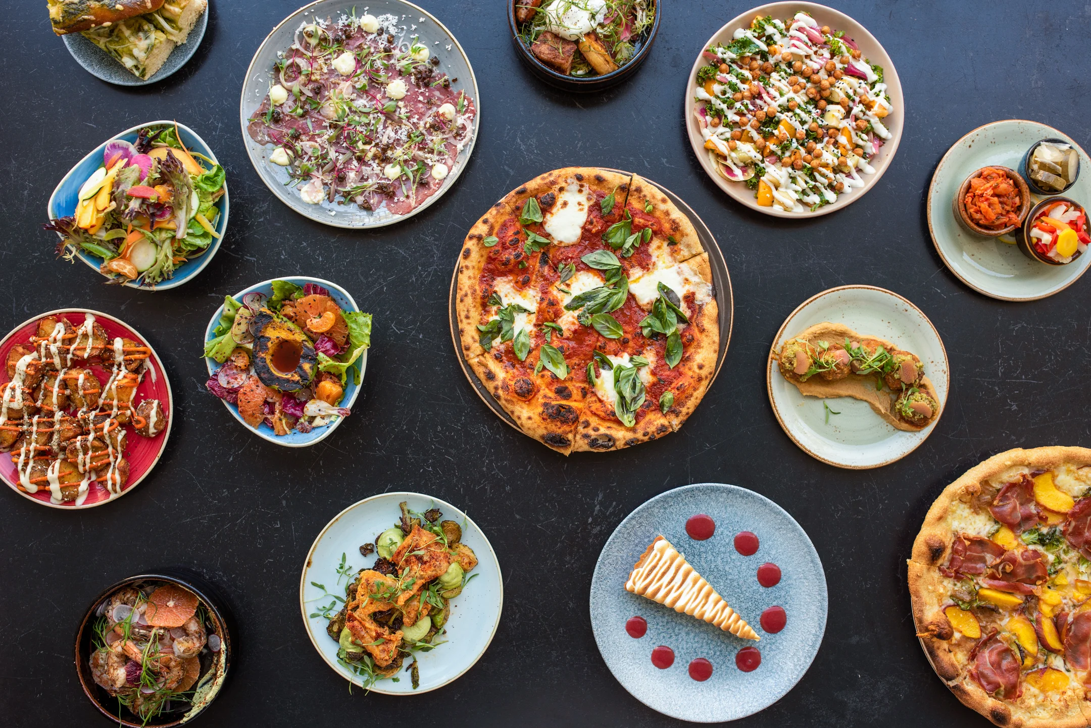 Assorted gourmet dishes including Margherita pizza and vibrant salads