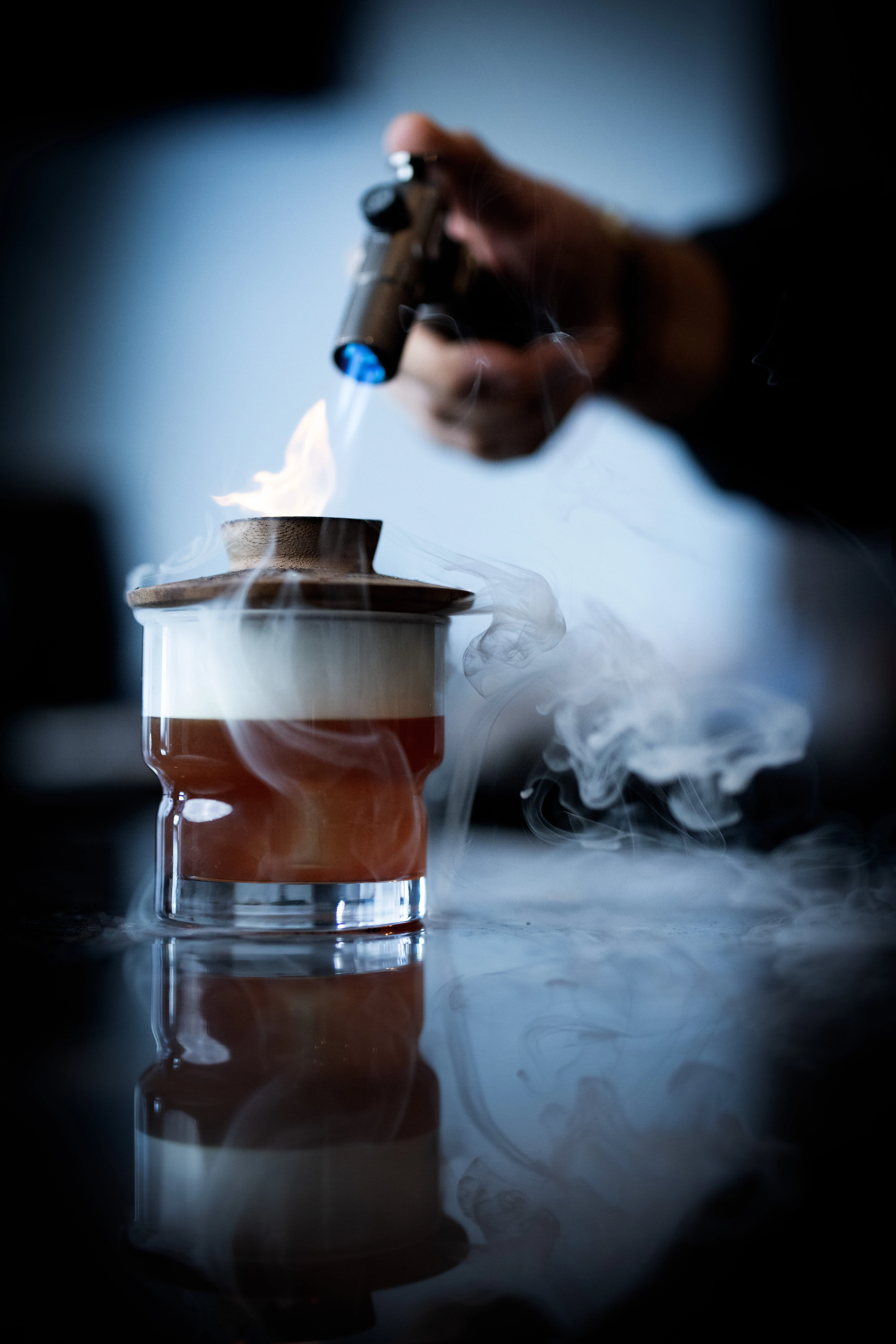 Bartender igniting a cocktail with smoke and flame