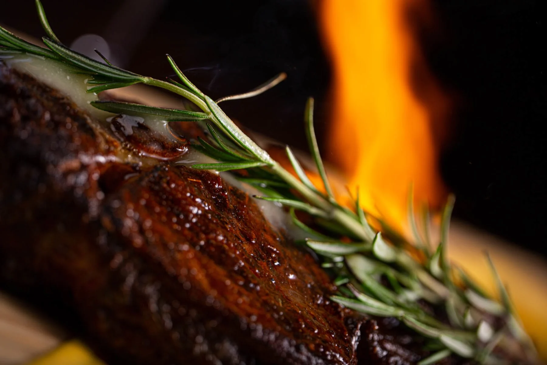 Grilled steak with rosemary garnish and flames