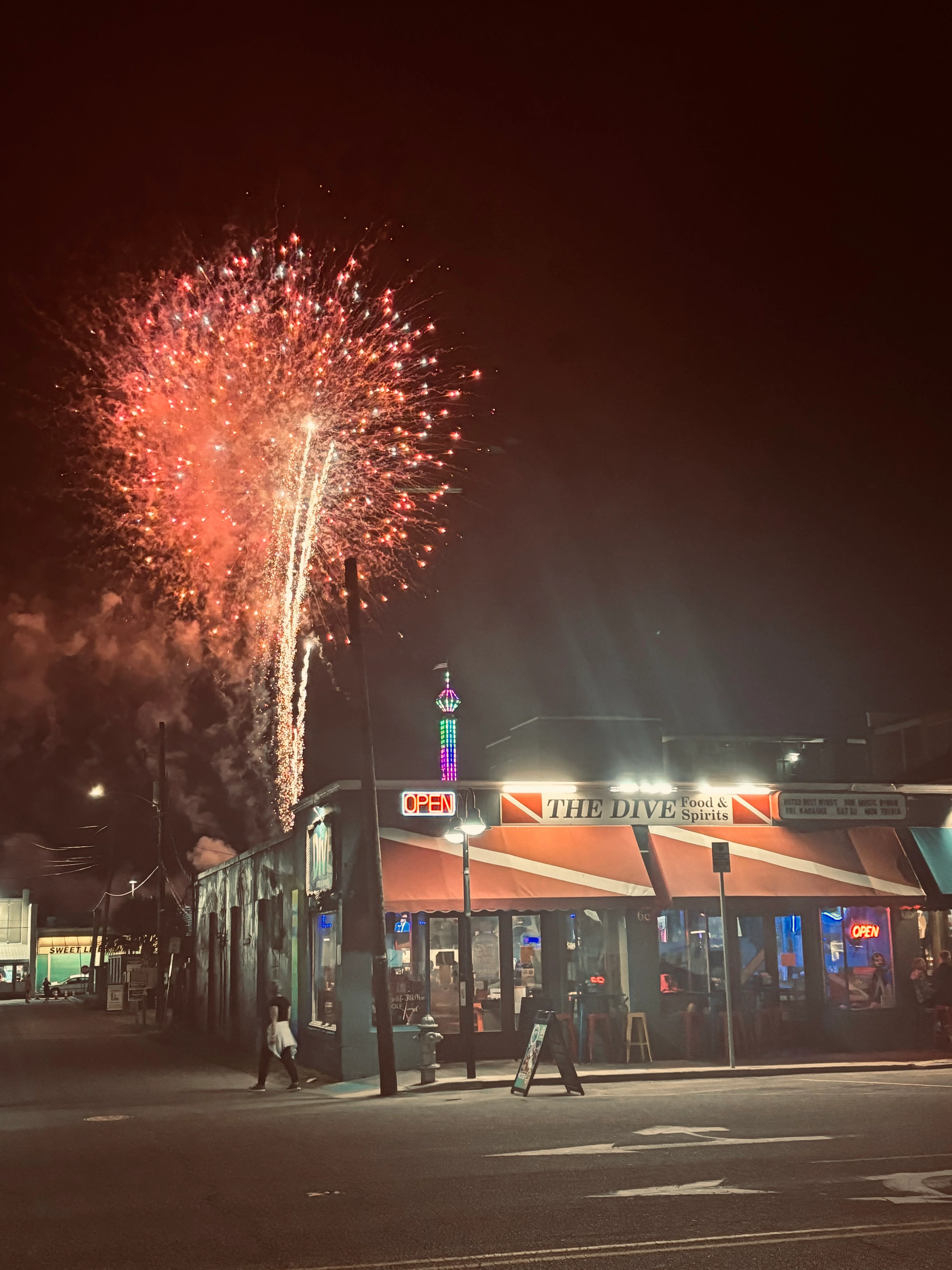Vibrant fireworks over a lively restaurant at night