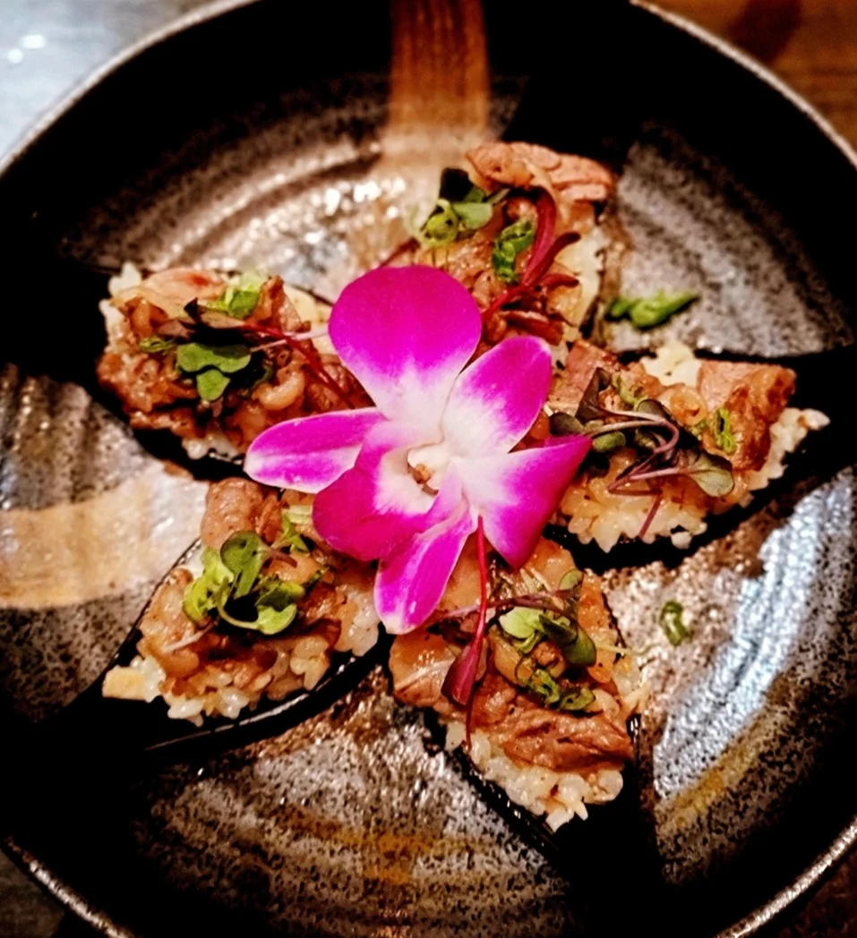 Japanese sushi with beef and edible flower garnish