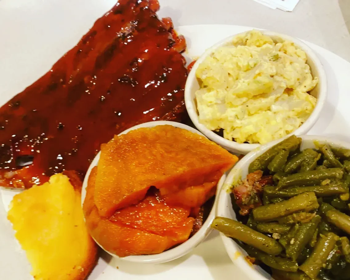BBQ ribs with sides of macaroni salad, sweet potatoes, and green beans