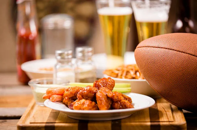Plate of buffalo chicken wings with beer and football