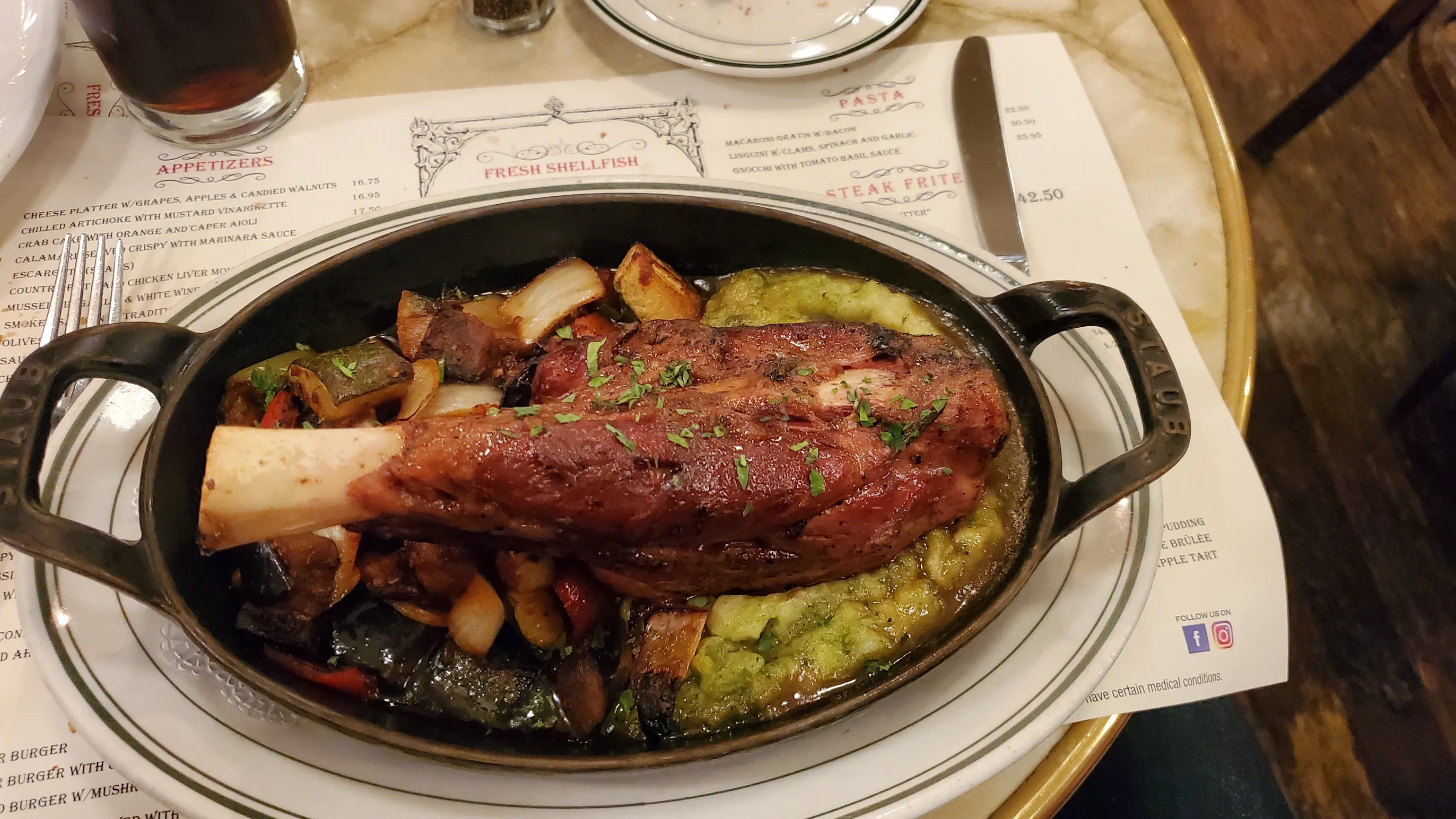 Braised lamb shank served with vegetables in a rustic restaurant setting