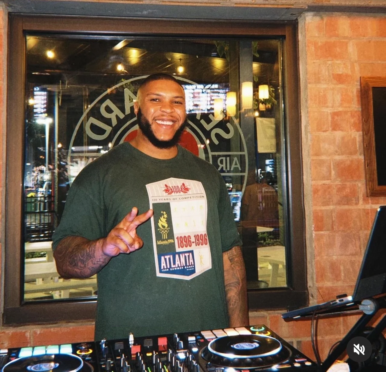 DJ smiling at a restaurant bar with turntables