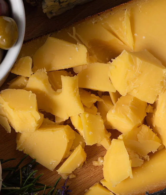 Cheddar cheese chunks on a wooden board