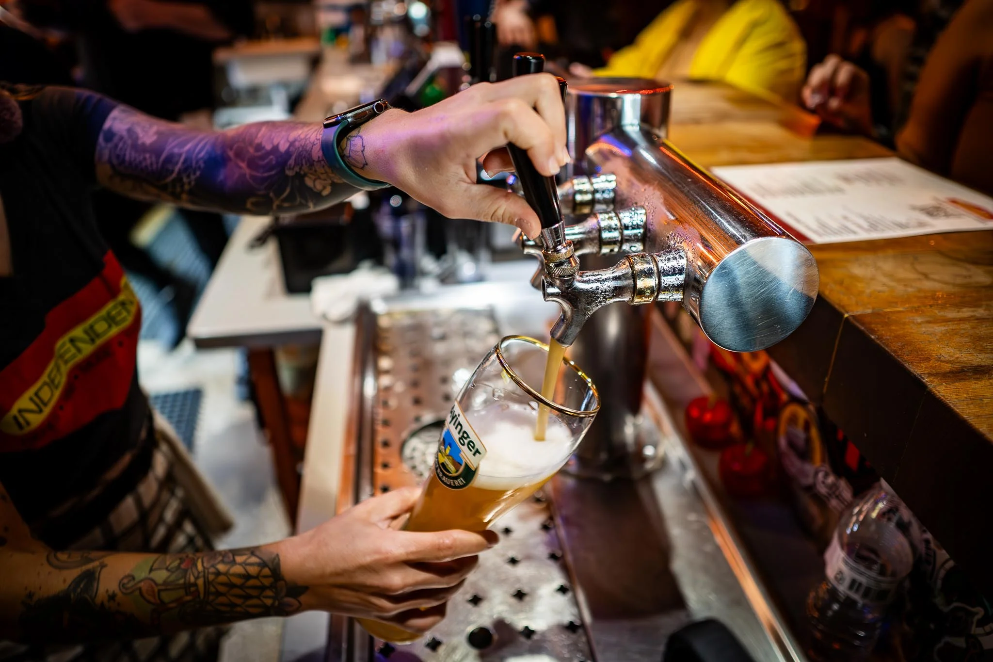 Bartender pouring a fresh beer into a glass at a lively bar