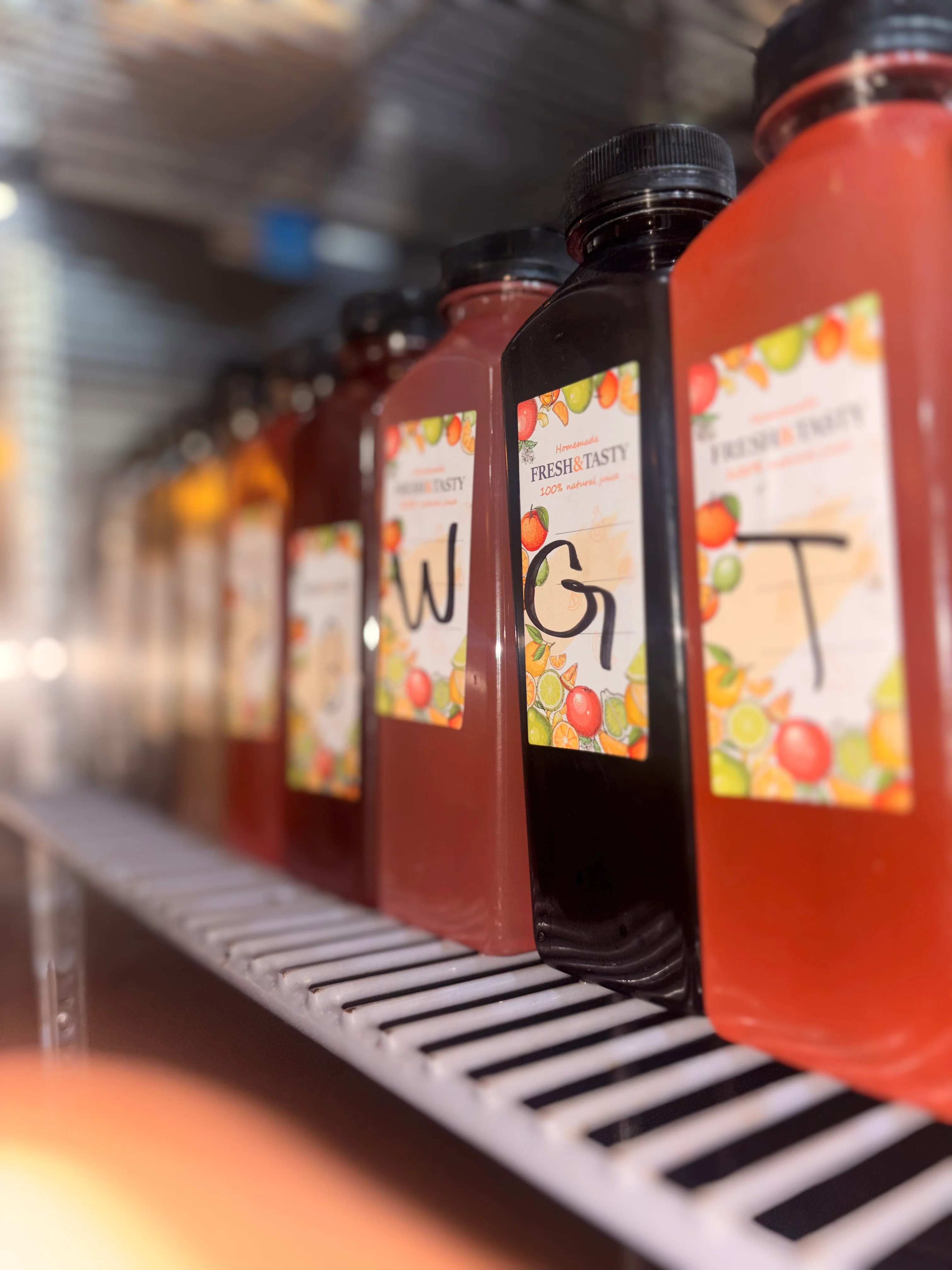 Assorted fresh juices in bottles on a refrigerator shelf