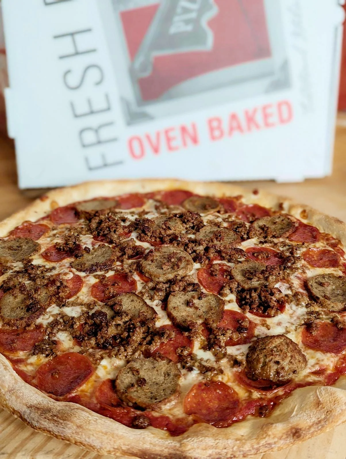 A large pizza topped with pepperoni and sausage, with a crispy crust.