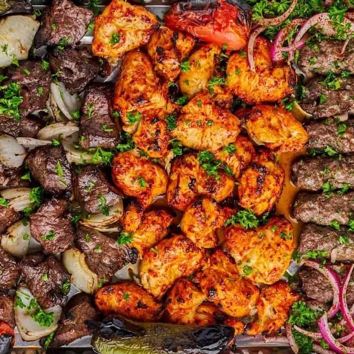 Middle Eastern mixed grill platter with kebabs, chicken, grilled vegetables, and onions