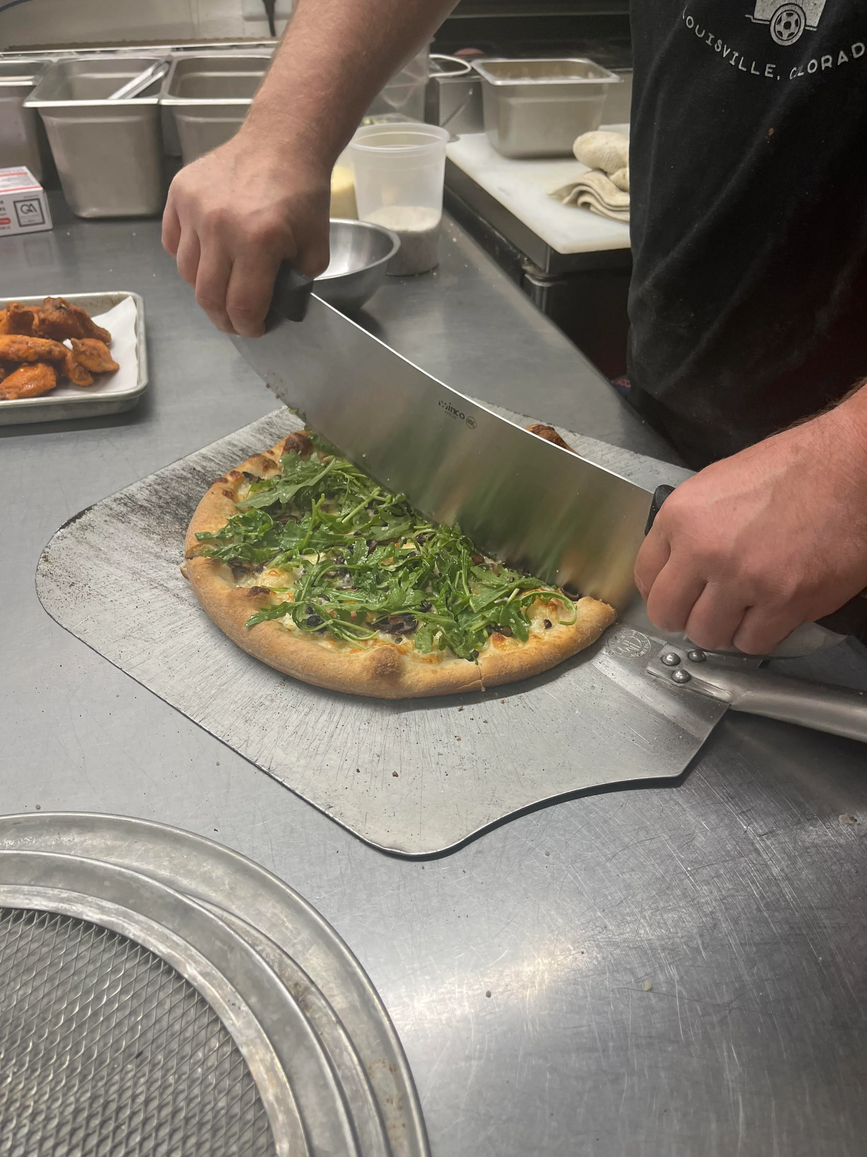 Freshly sliced arugula pizza in a restaurant kitchen