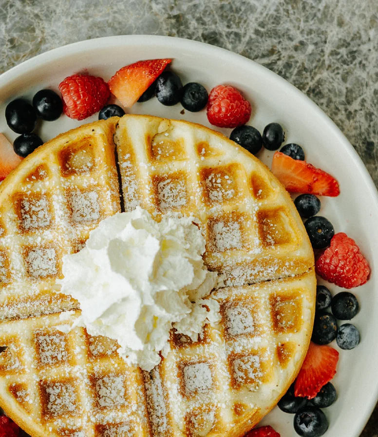 Belgian waffles topped with whipped cream and fresh berries