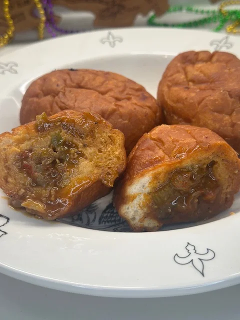 A plate with fried dough balls containing a savory filling, accompanied by a few whole pieces.