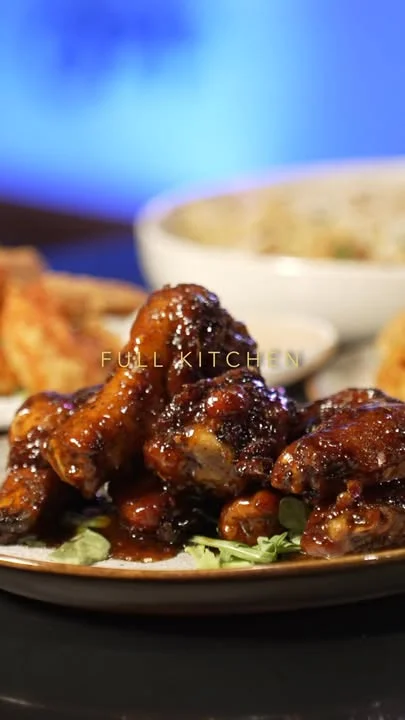 A mouthwatering plate of glazed chicken wings served with a side of flavorful rice and garnished with green herbs.