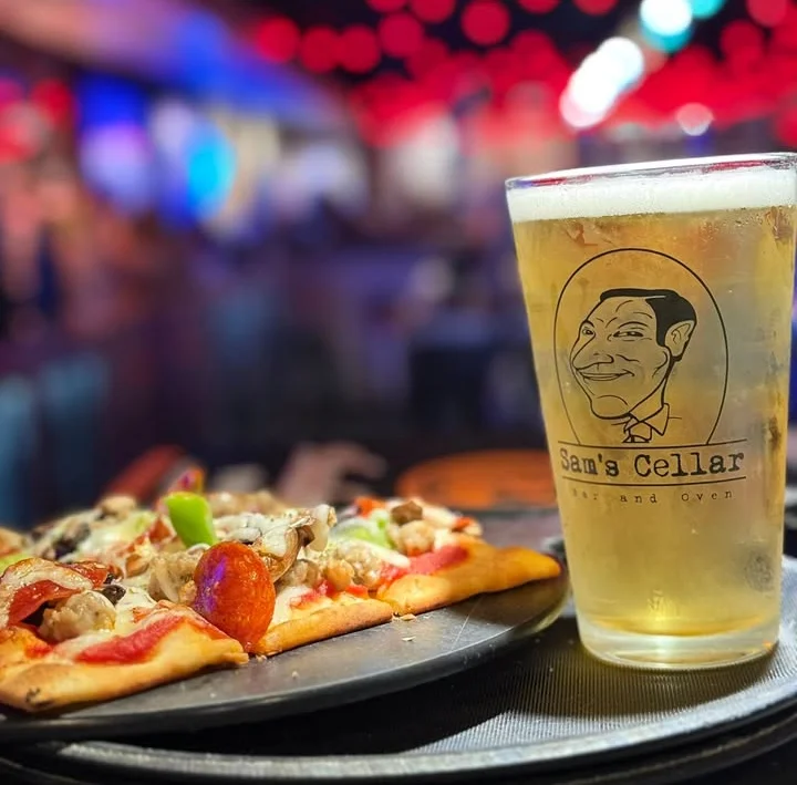 Pepperoni pizza served with a cold beer in a lively bar setting