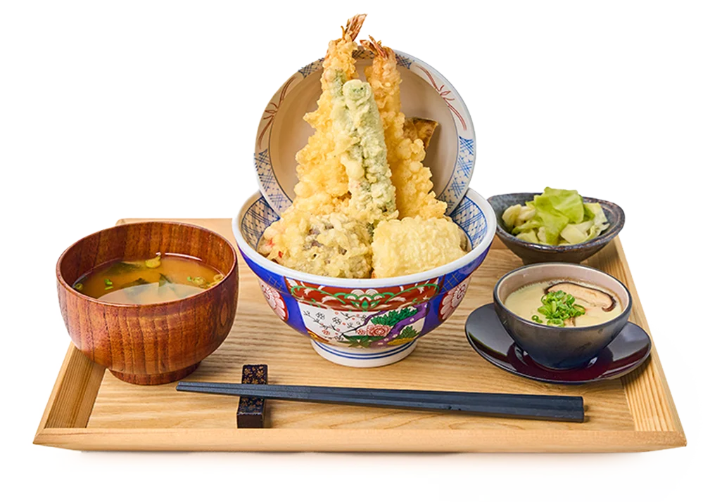 A vibrant Kohaku Tendon meal set is presented on a light wooden tray, featuring a towering bowl of golden-crisp tempura over rice.