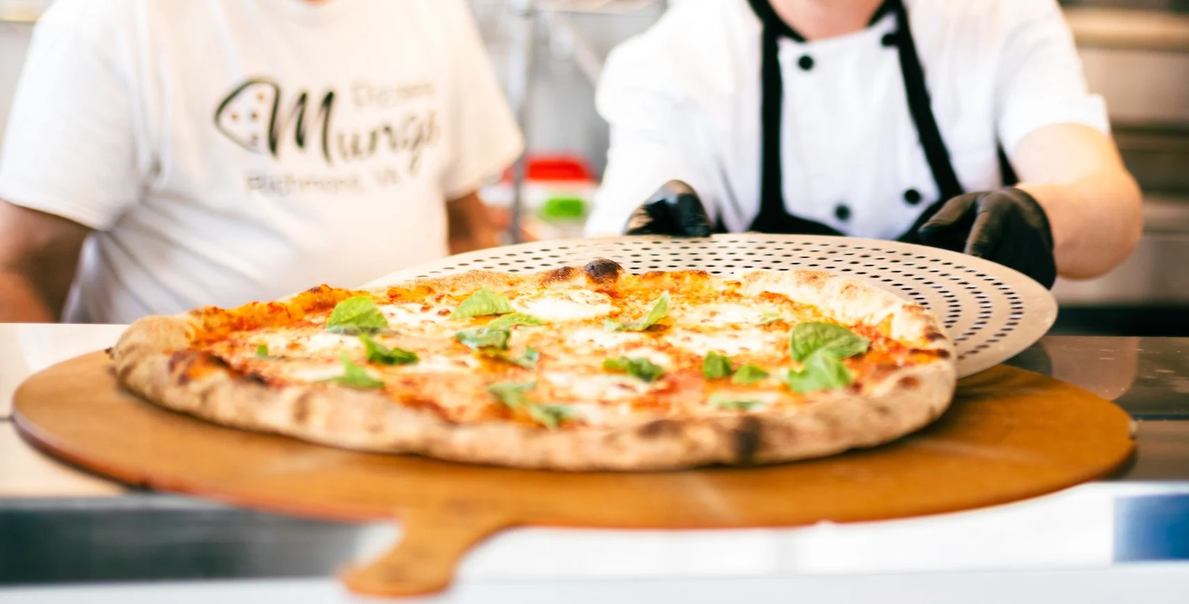 Pizza being pulled from a commercial oven
