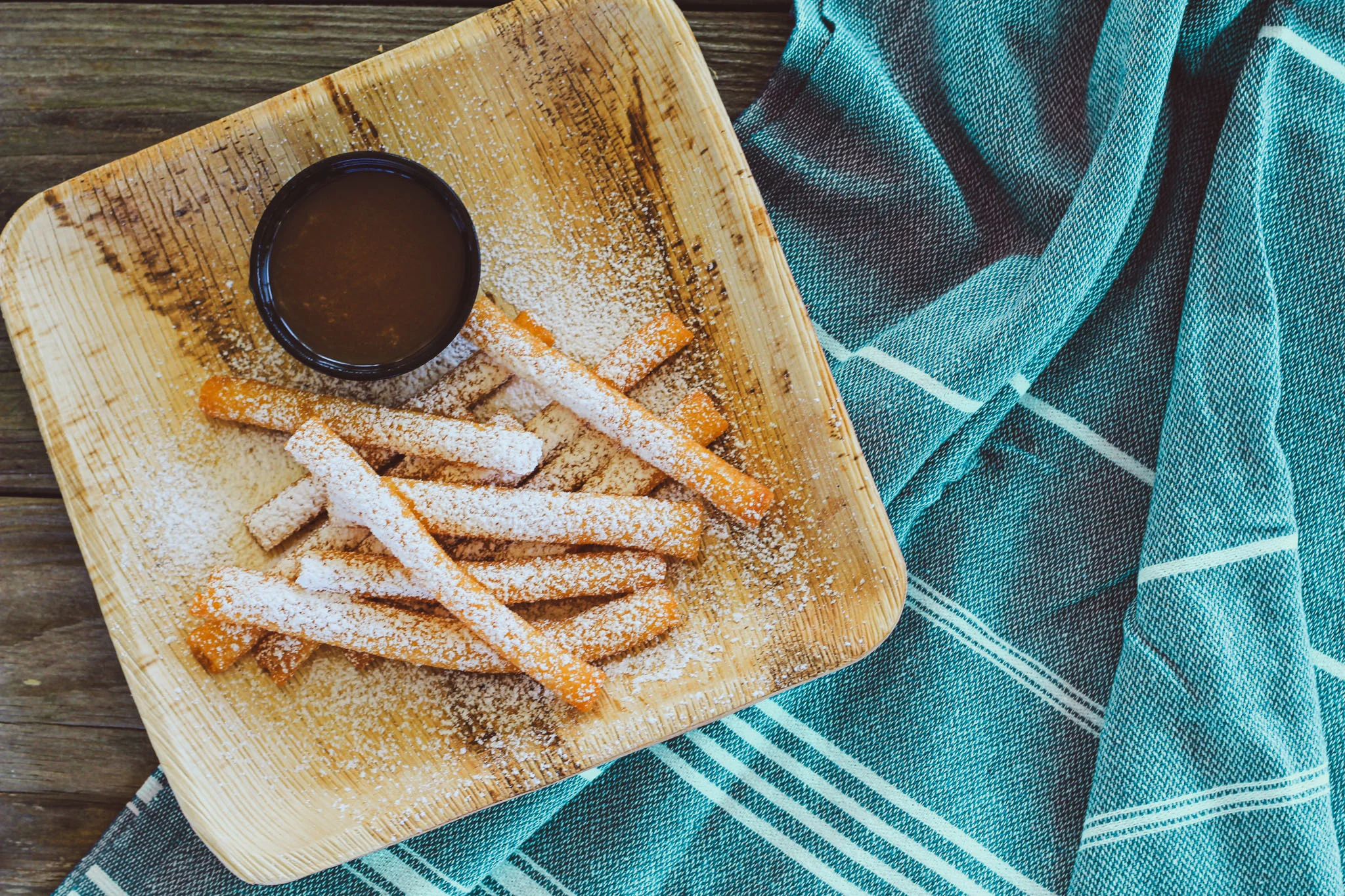 Cinnamon sugar churros with chocolate dipping sauce on a wooden platter