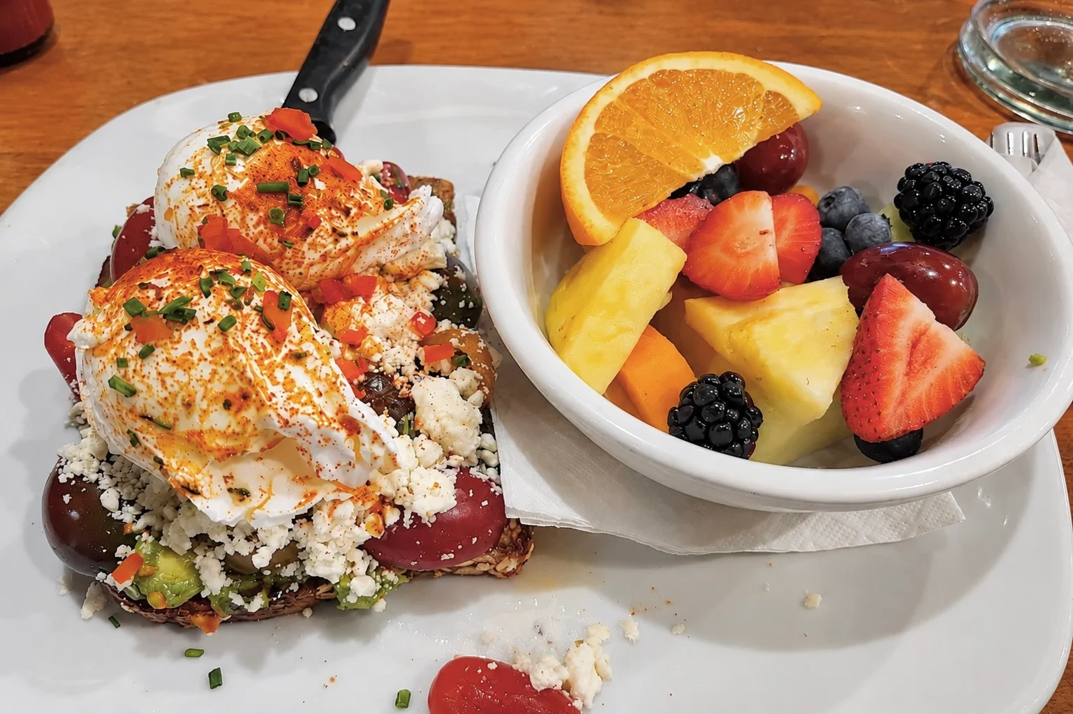 Avocado toast with poached eggs and fresh fruit salad