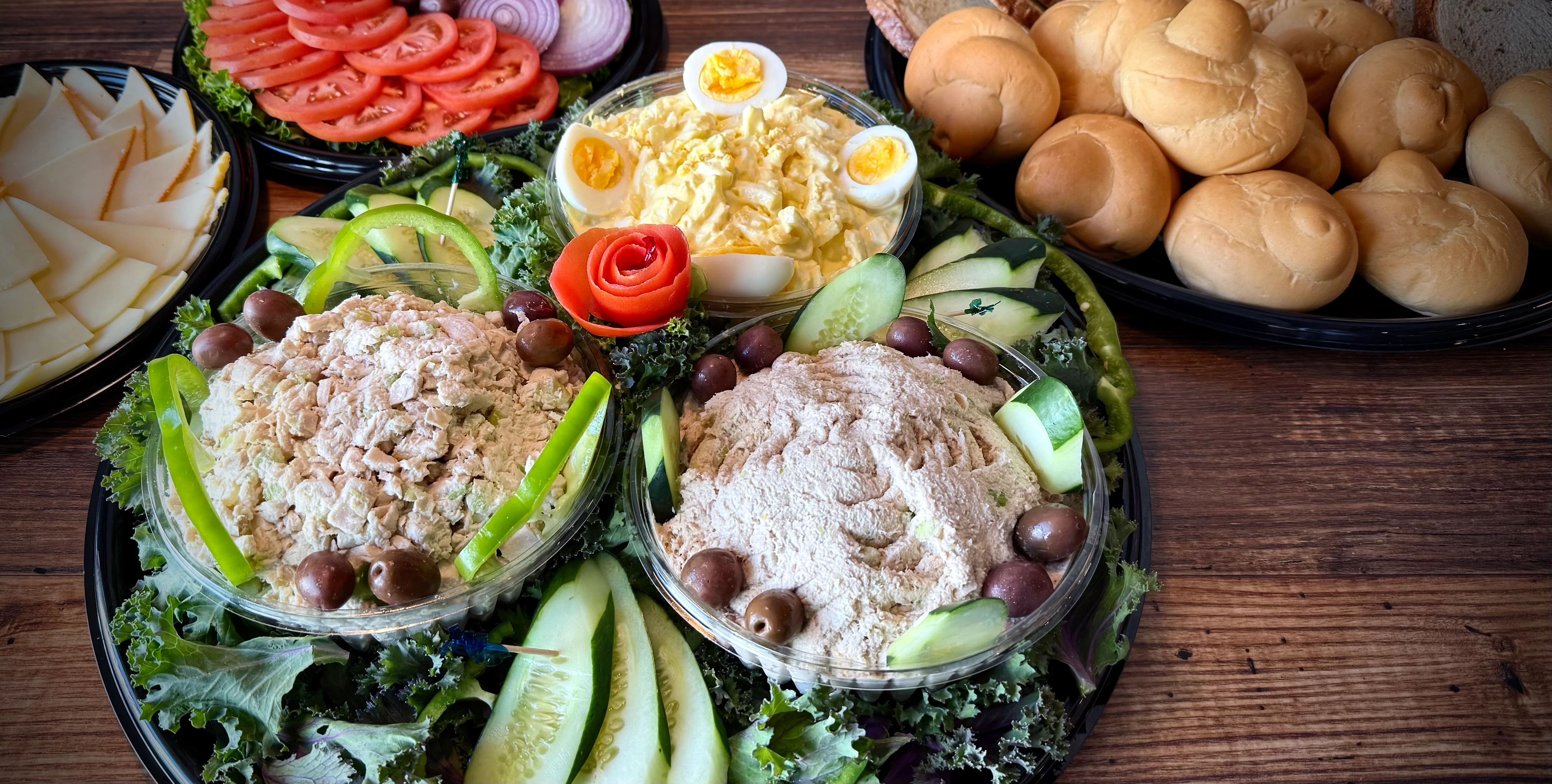 Catering platter with tuna salad, egg salad, bagels, and fresh vegetables.