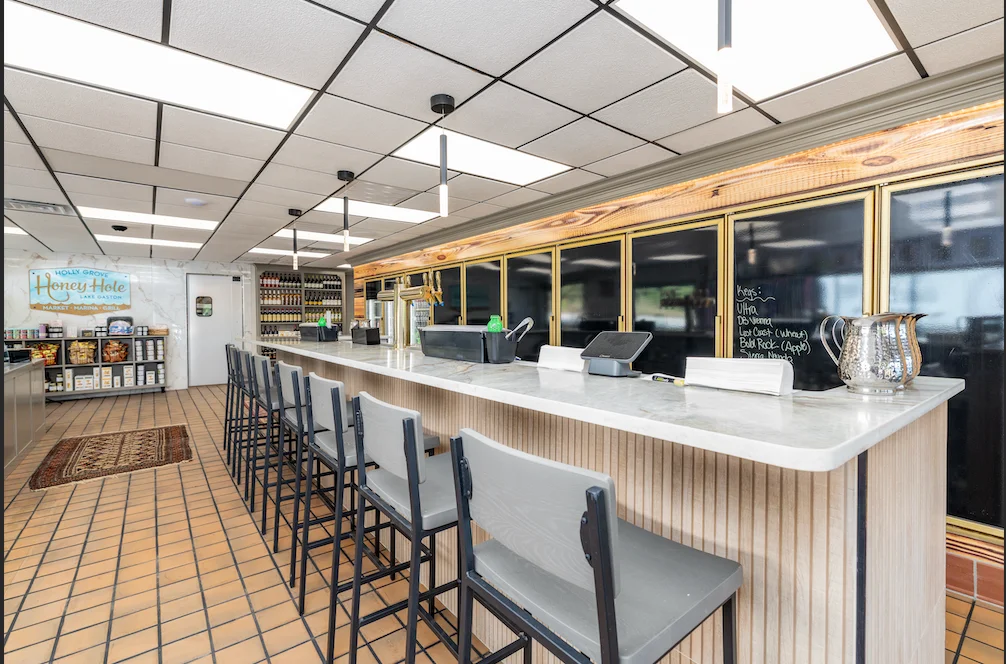 Interior of Honey Hole restaurant with bar seating and shelves of products.