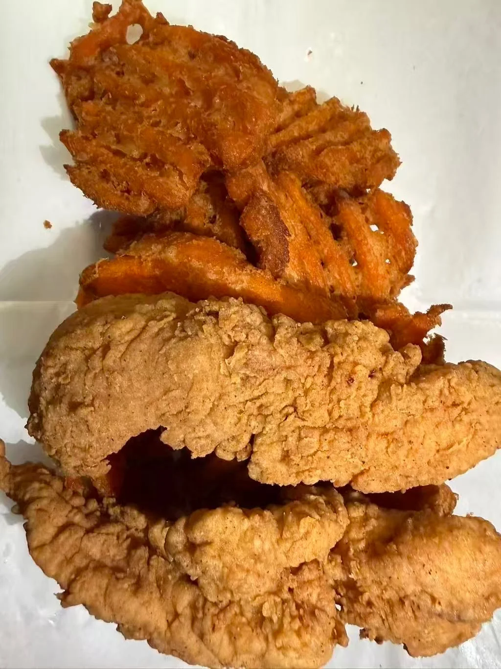 A plate with various pieces of fried items, including battered and crispy fish or chicken fillets.