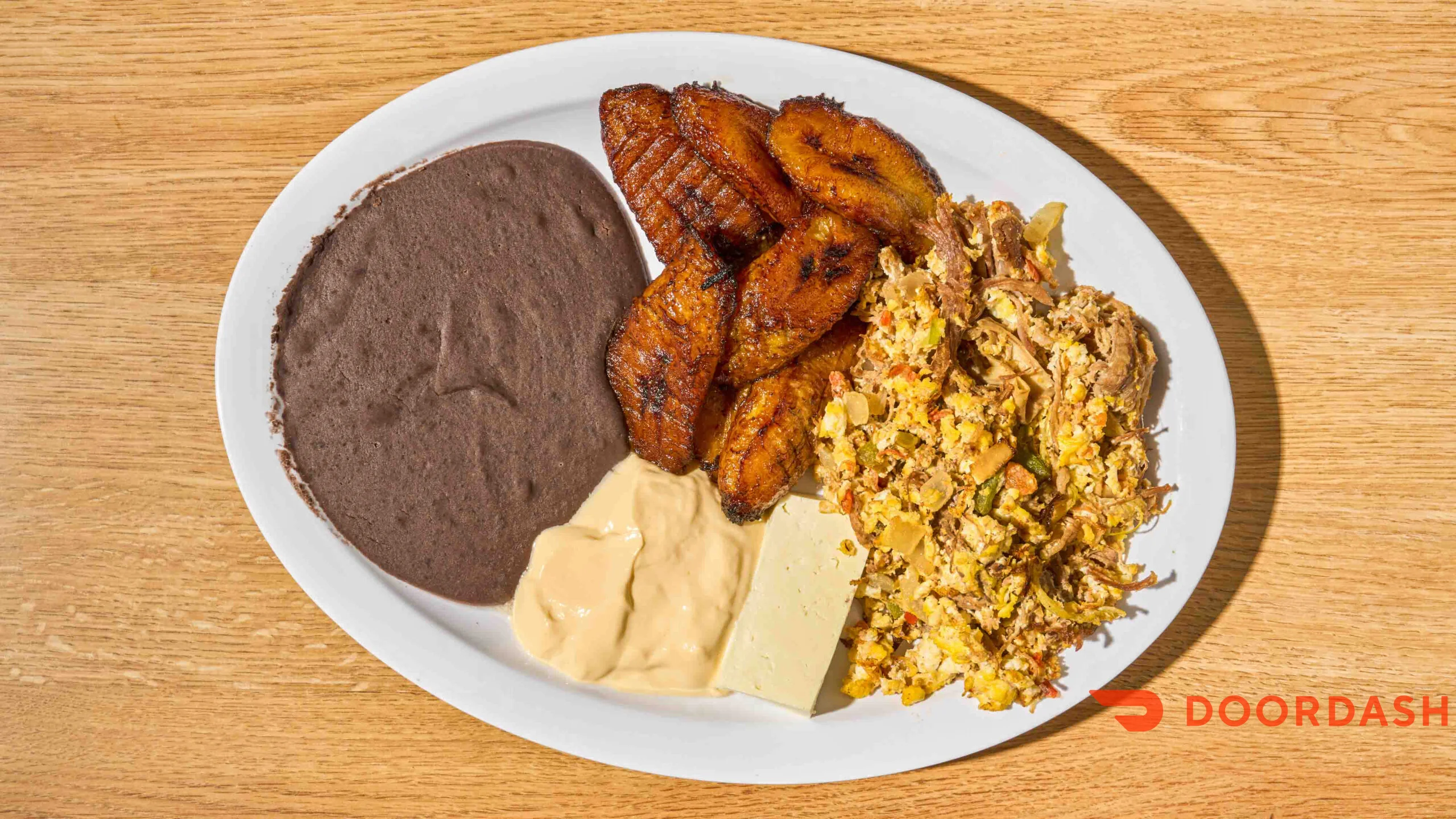 Plate of plantains, black beans, cheese, and scrambled eggs.