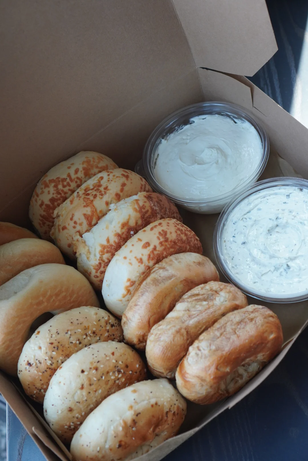Assorted bagels with cream cheese dips in a takeout box
