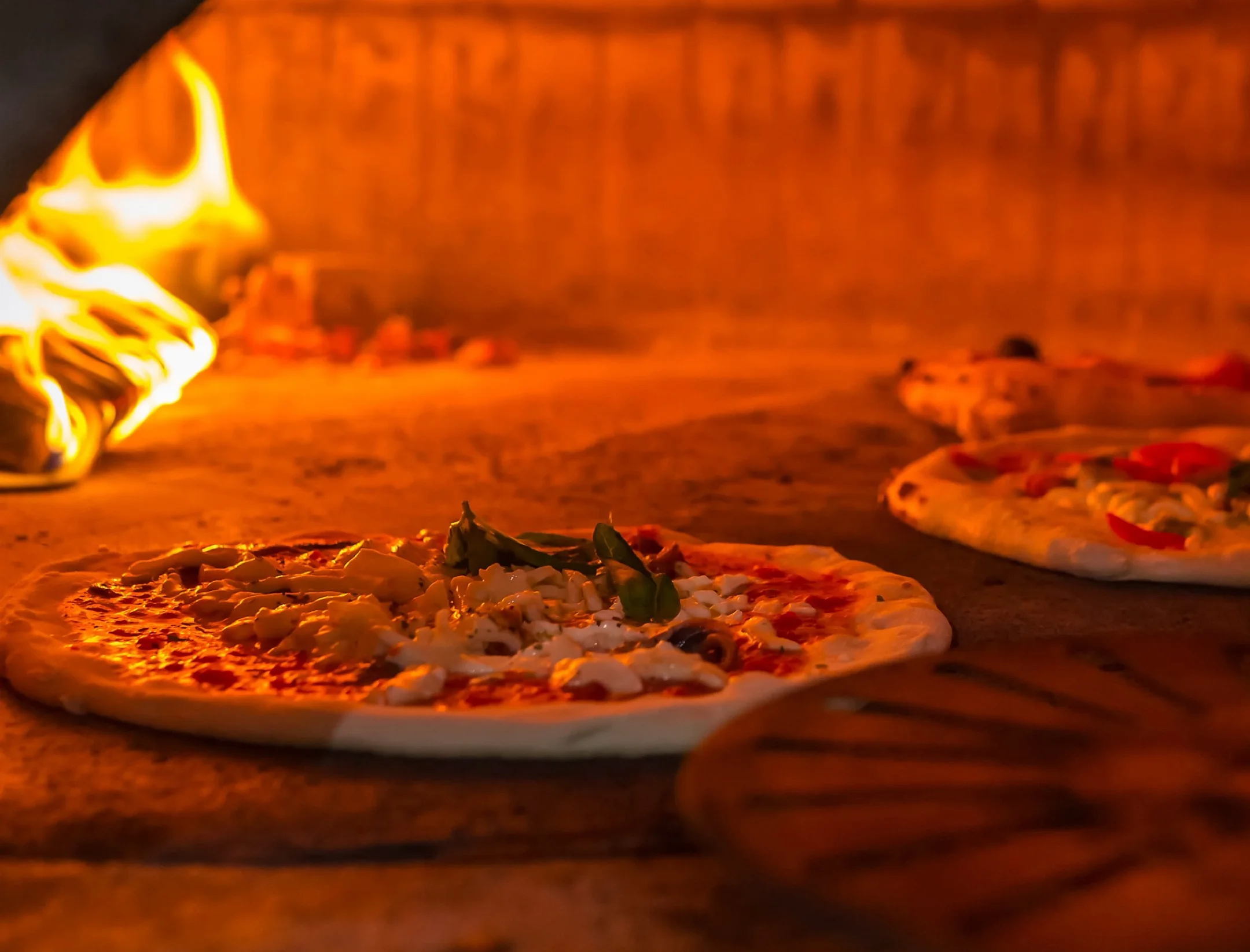 Wood-fired Margherita pizza baking in a traditional oven