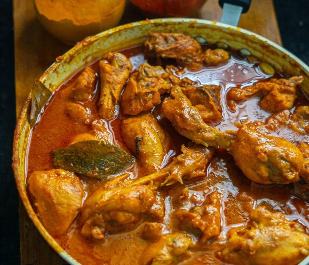 A pot of flavorful chicken curry with spices and herbs.