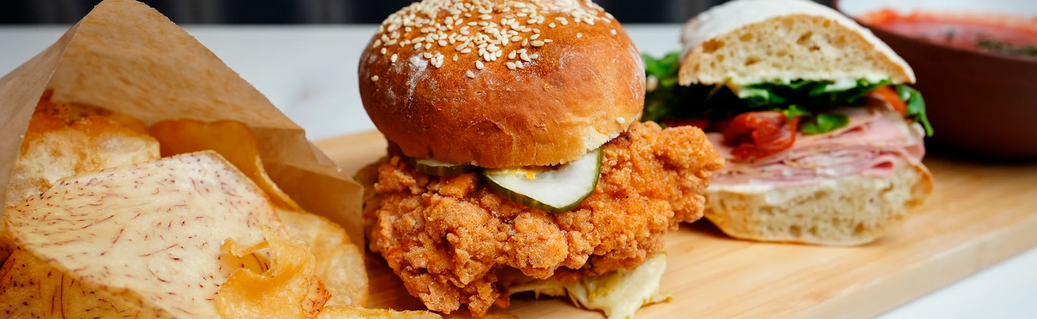 Southern fried chicken sandwich with crispy chips on a wooden platter