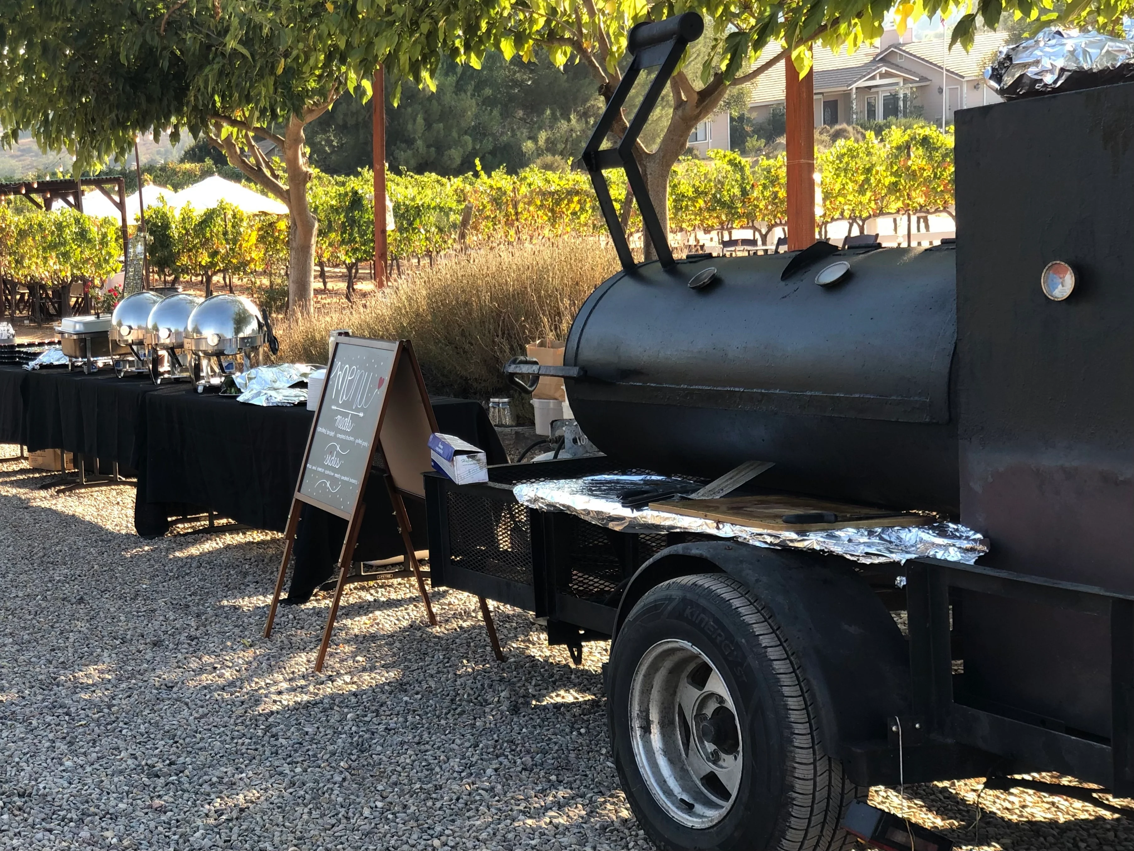 Outdoor barbecue setup with a smoker and buffet tables