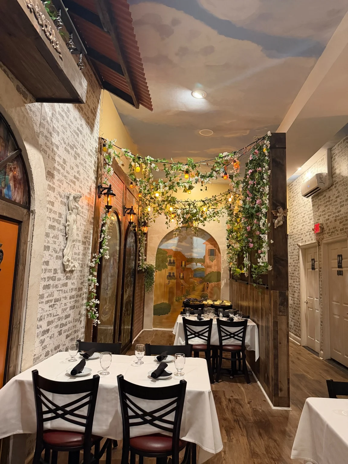 Villa Italiana dining room with hand-painted mural, floral archways and white tablecloths