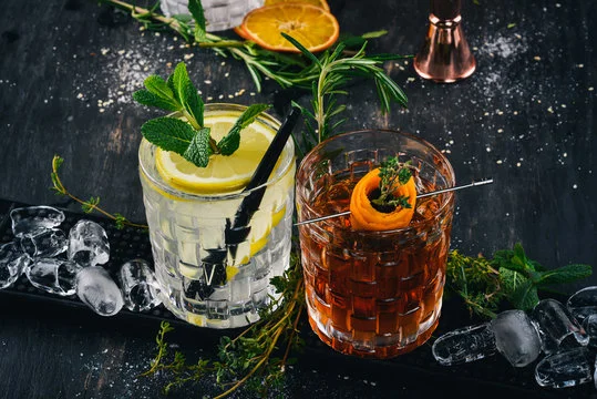 Craft cocktails on a bar counter with fresh herbs and ice