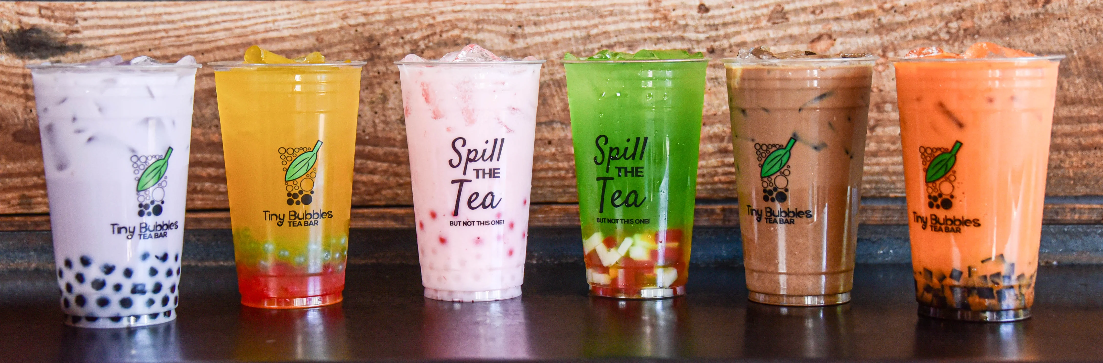 Colorful bubble tea drinks in clear cups on a rustic wooden table