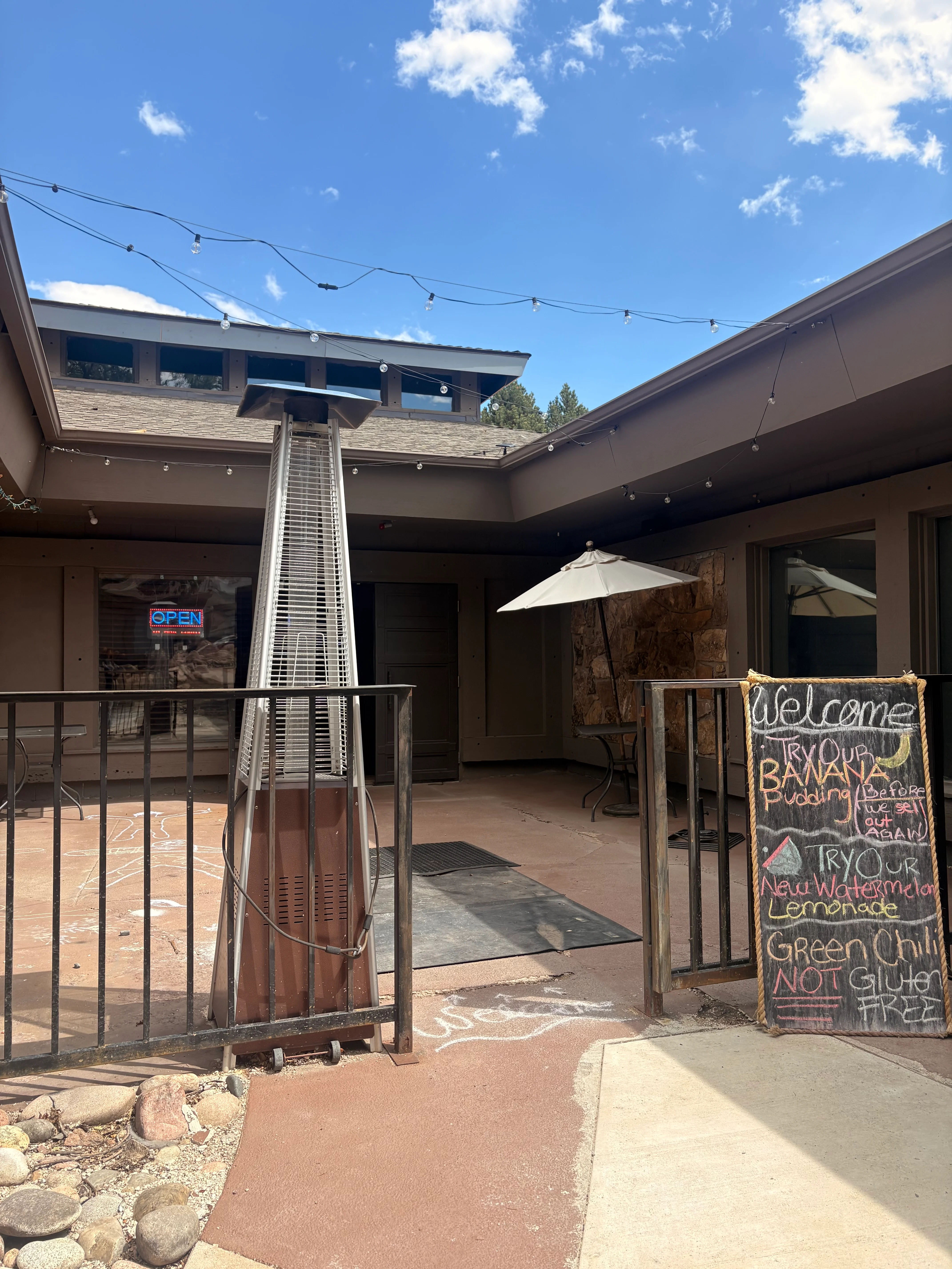 Outdoor restaurant entrance with patio heater and welcoming signage