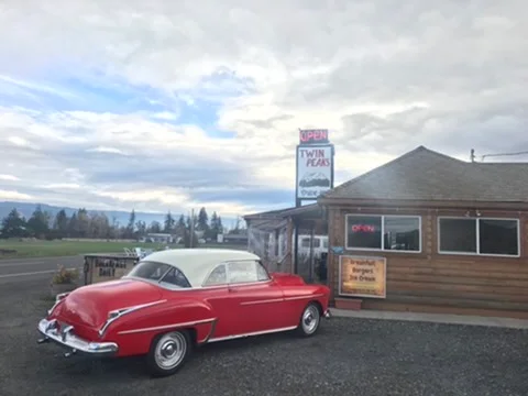 Classic red vintage car parked outside a rustic diner