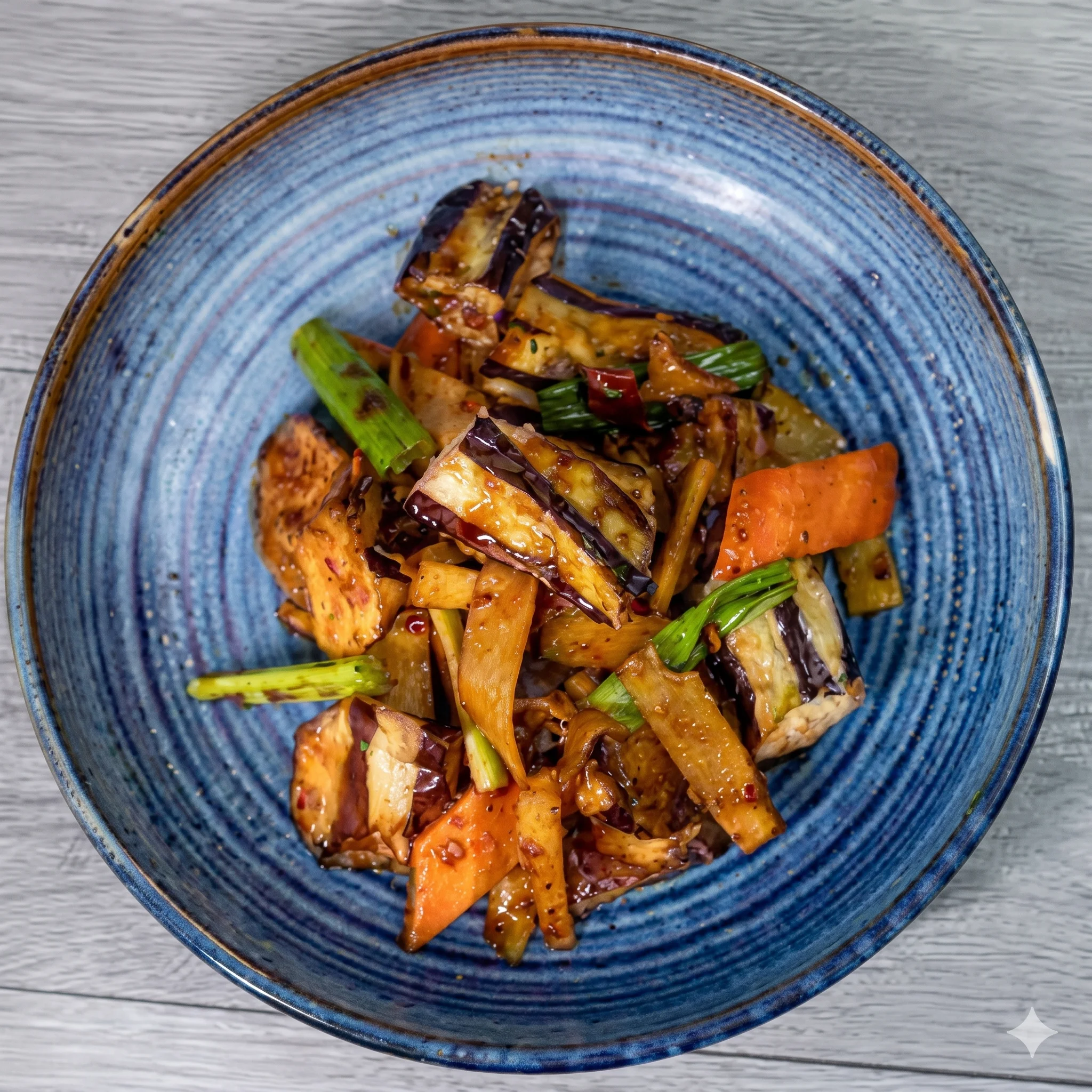 Stir-fried eggplant and vegetables in a blue bowl.