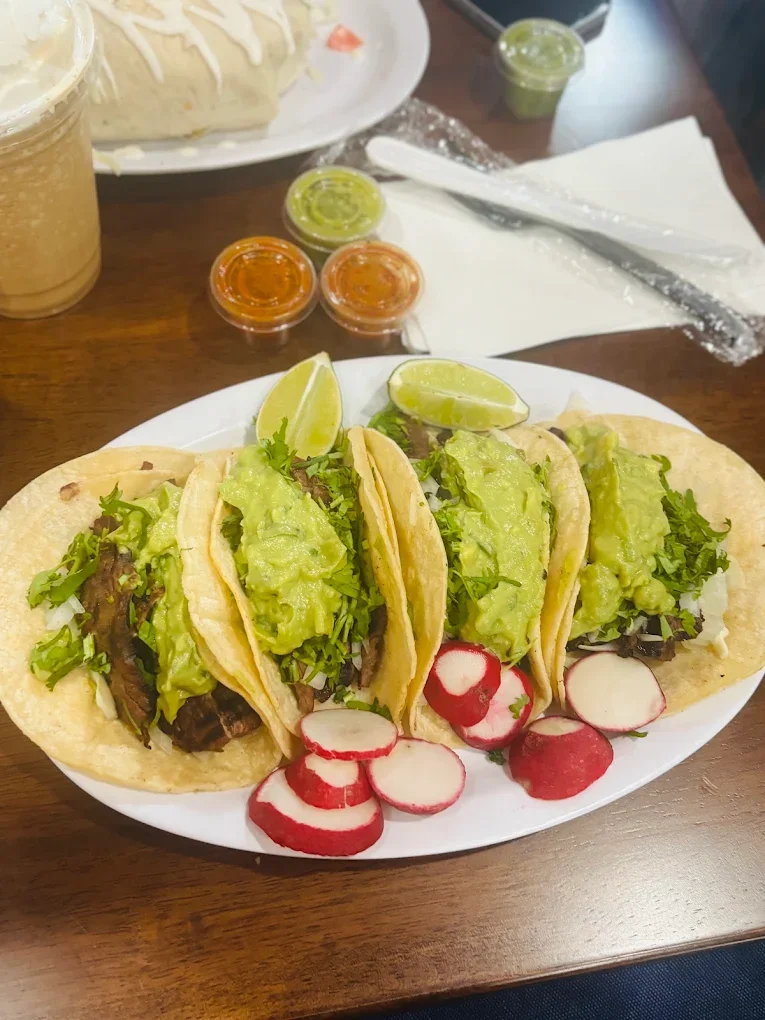 Four delicious tacos from El Ranchito Poblano in Brooklyn, served on soft tortillas and topped with fresh avocado slices and cream.