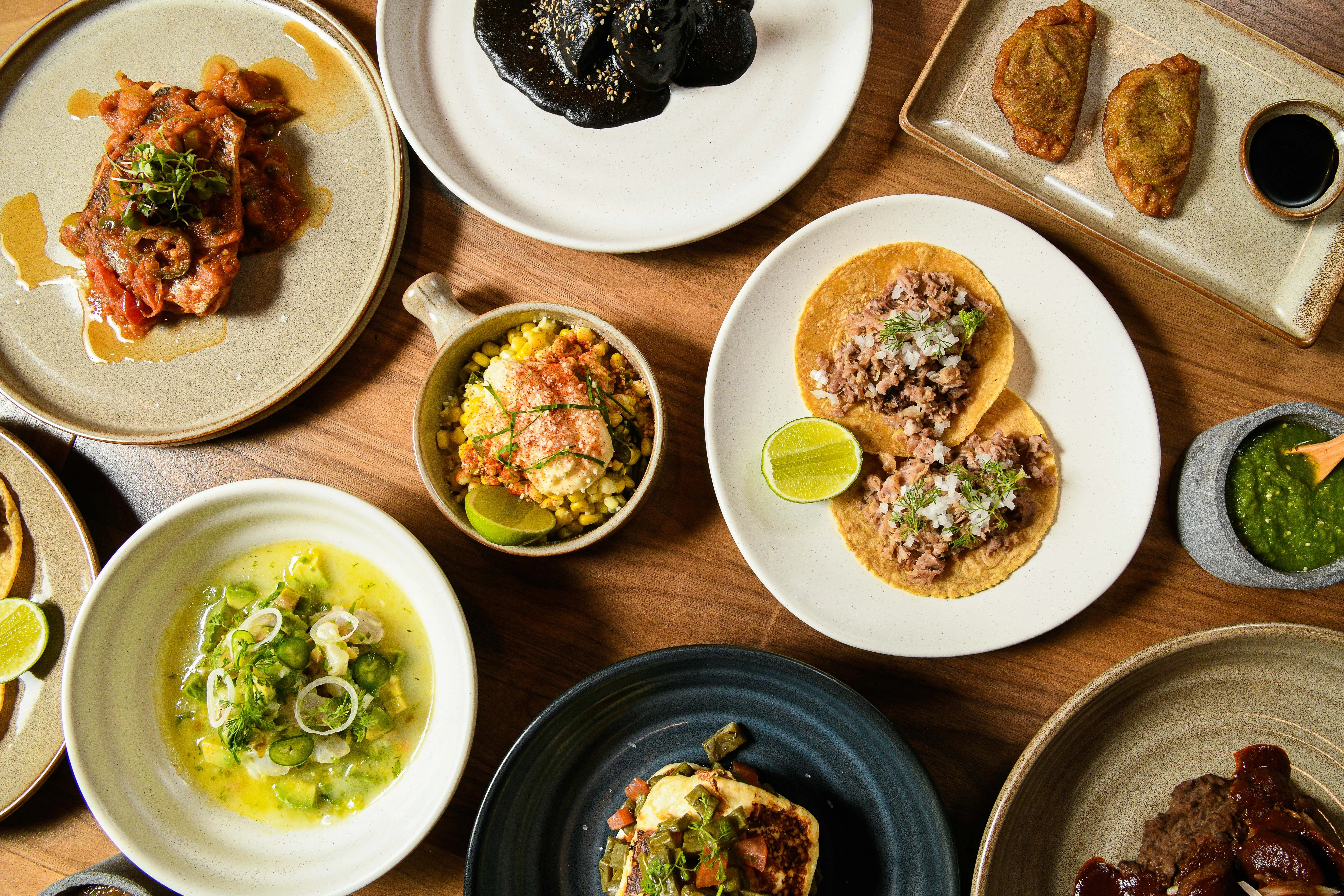Assorted Mexican dishes including tacos and esquites