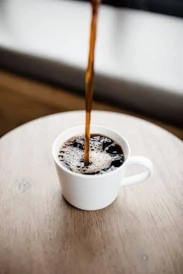 Freshly brewed coffee pouring into a white cup