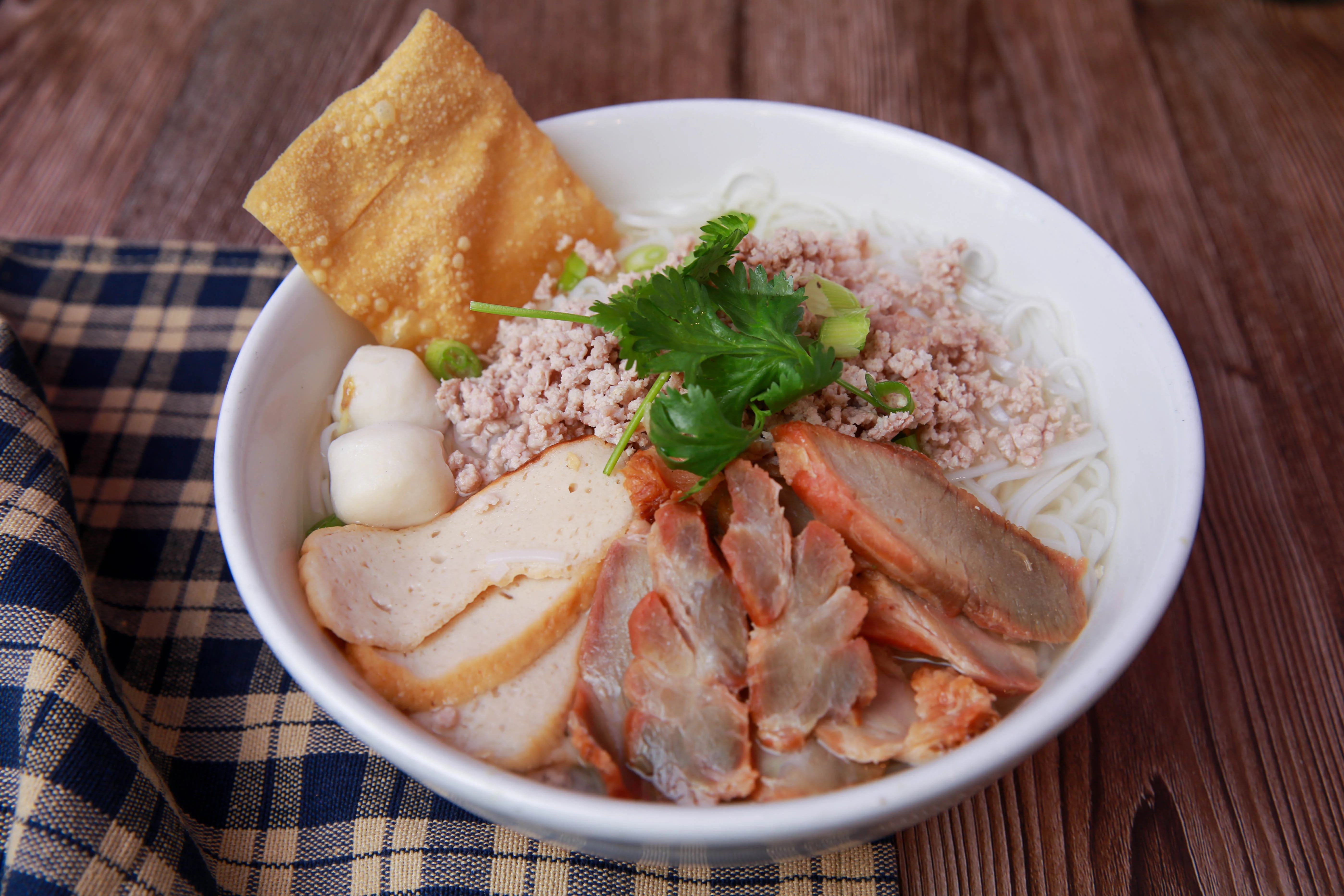 Bowl of Thai boat noodles with meat and herbs