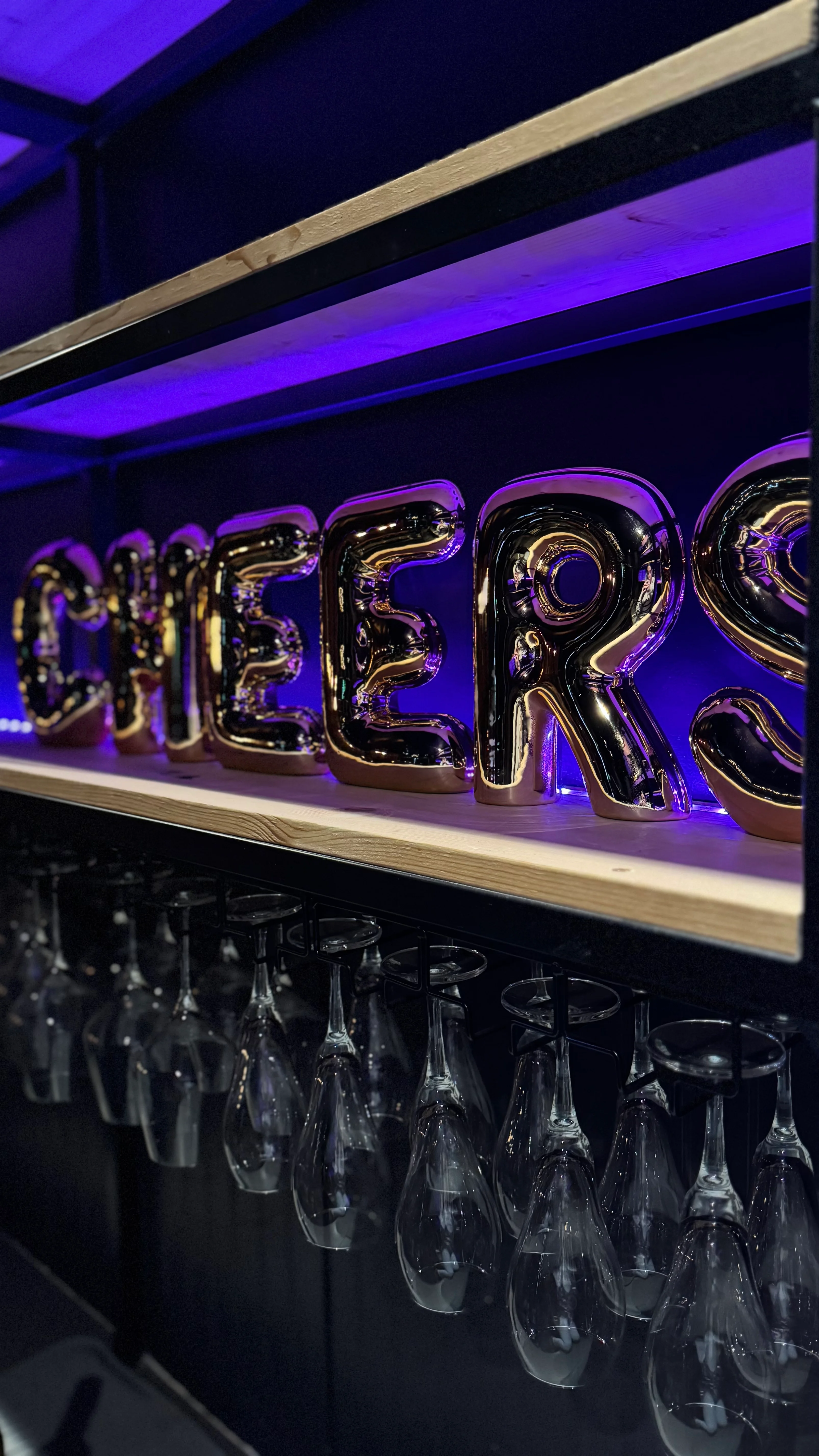 Stylish bar display with 'CHEERS' sign and hanging glasses