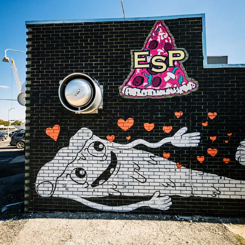 Colorful mural featuring pizza and playful characters on a brick wall