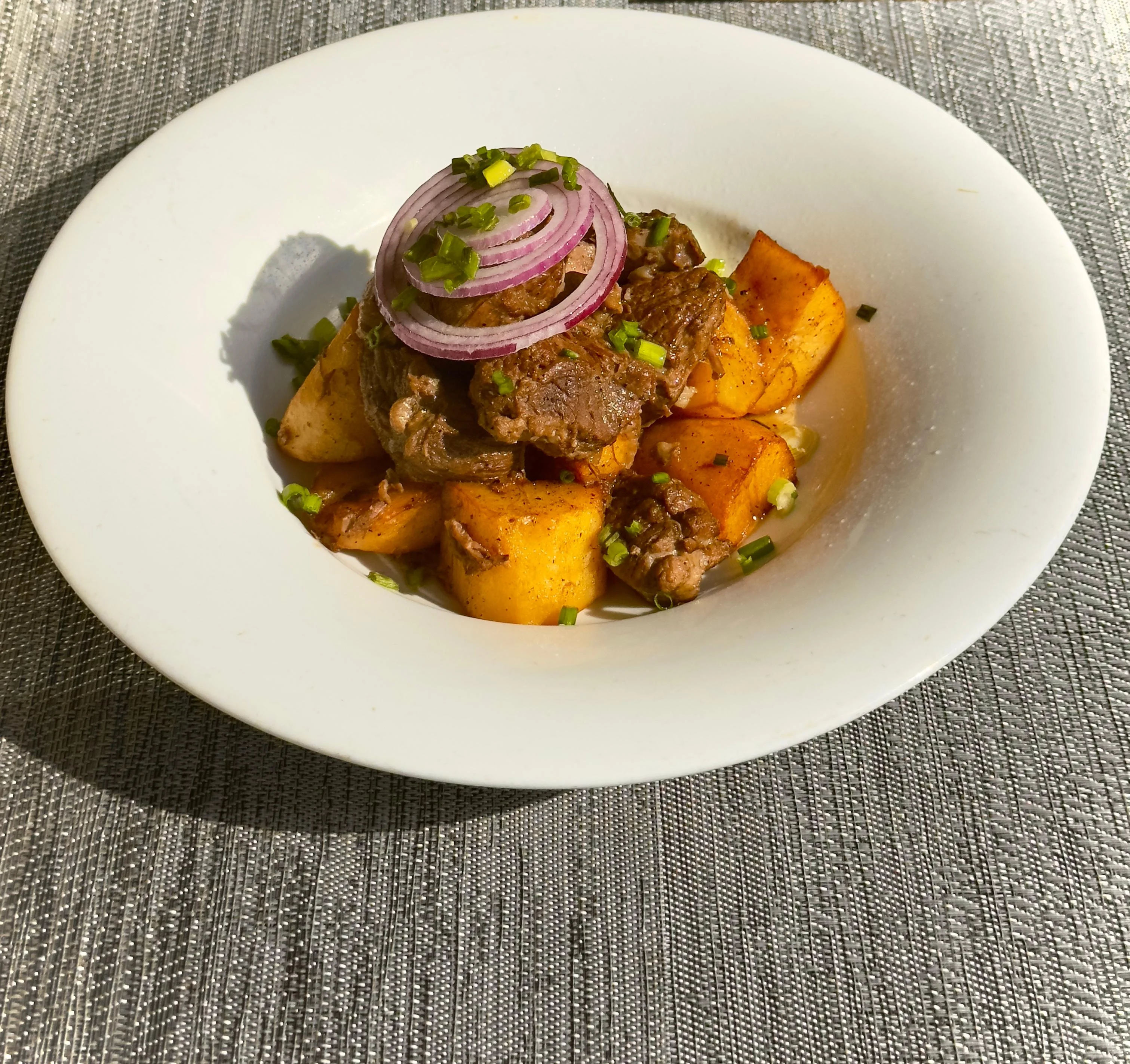 Savory Ghanaian beef and yam stew garnished with onions