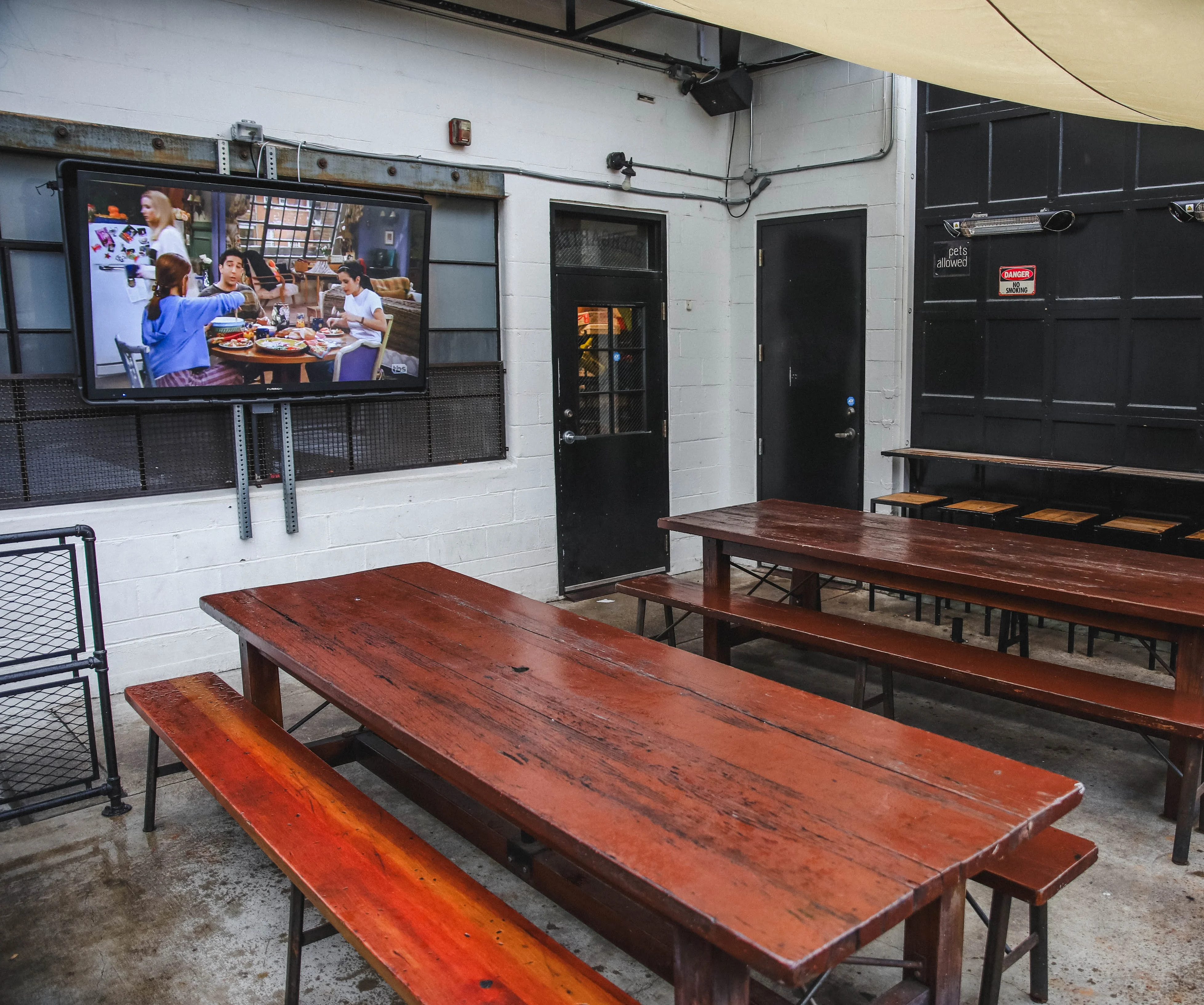 Outdoor dining area with wooden tables and a TV screen