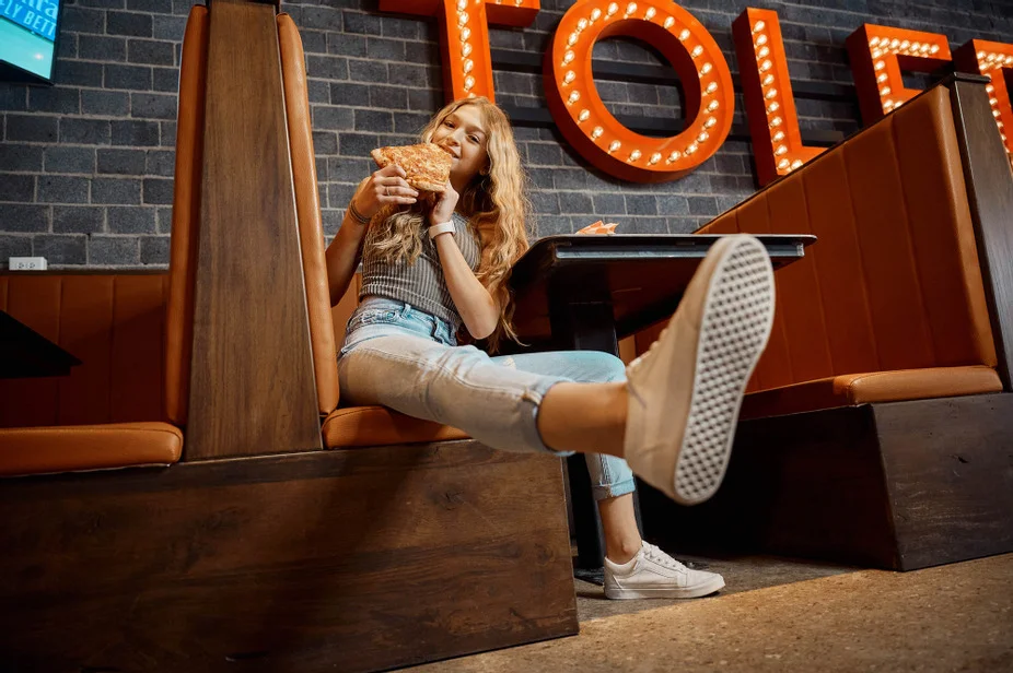 Young woman enjoying a slice of pizza in a cozy restaurant setting