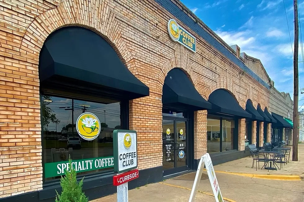 Exterior of a specialty coffee shop with outdoor seating and signage.